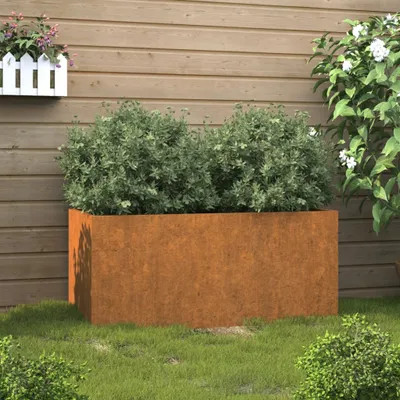 A rectangular planter made of corten steel filled with green plants, placed on a lawn in front of a wooden wall.
