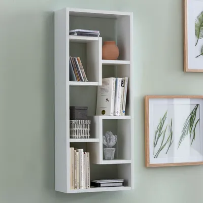 A white wall-mounted shelf unit with various items on display.