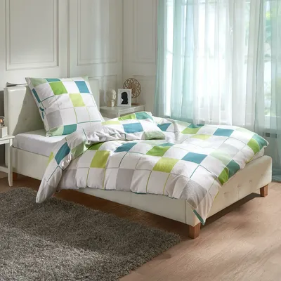 A neatly made bed with a patterned duvet and pillow in a bedroom setting.