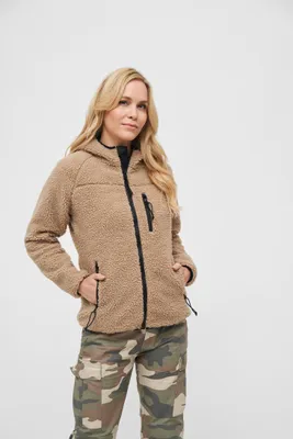 A woman wearing a teddy fleece jacket and camouflage pants against a white background.