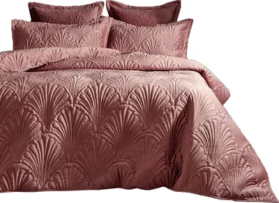 A close-up view of a rose-colored velvet bedspread and pillows with a fan-like quilted pattern.