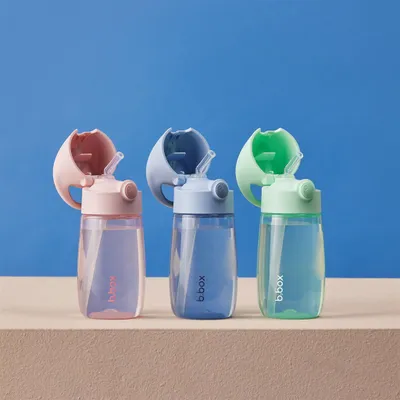 Three children's water bottles with straws are lined up against a blue background.