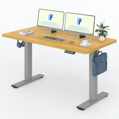A standing desk with dual monitors, keyboard, mouse, headphones, and a plant.