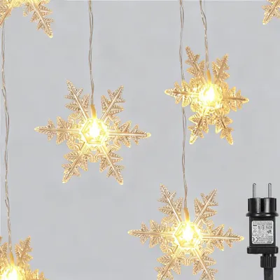 A string of snowflake-shaped LED lights hanging against a light gray background, with a power adapter visible on the right.