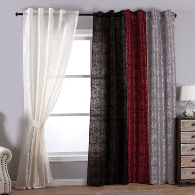 Several curtains of different colors are displayed in front of a window, with a dresser and lamp to the right.