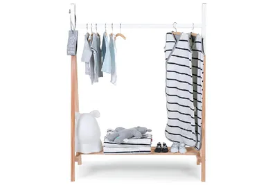 A wooden tipi-shaped clothes rack for children, with baby clothes and accessories displayed.