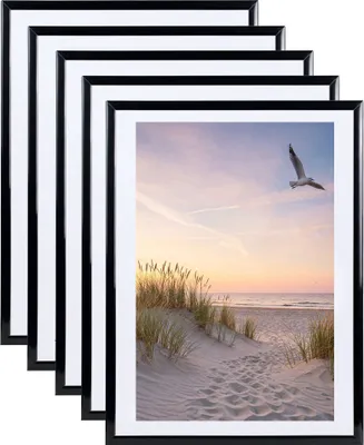 A stack of black picture frames, with one frame showing a beach scene at sunset.