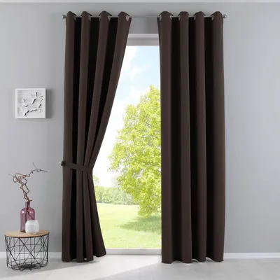 A pair of brown blackout curtains are shown tied back, revealing a window with a view of trees and a grassy field.