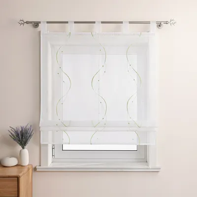 A white sheer curtain with green wavy embroidery and beads hangs on a window.