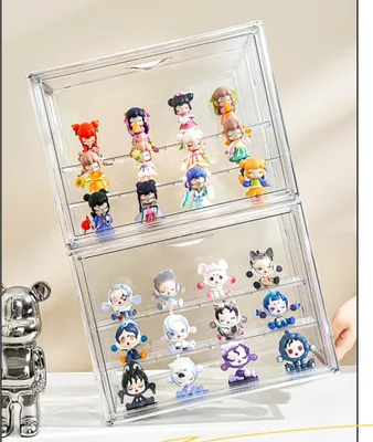 A clear acrylic display case filled with small collectible figures, tilted to show multiple shelves and rows of figures. A silver bear-shaped figurine is partially visible on the left.