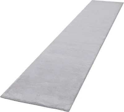 A long, narrow, light gray rug is shown from a diagonal perspective against a white background.