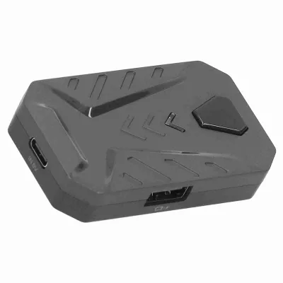 A close-up studio shot of a black gaming adapter. The adapter is angled to show its ports and textured surface.