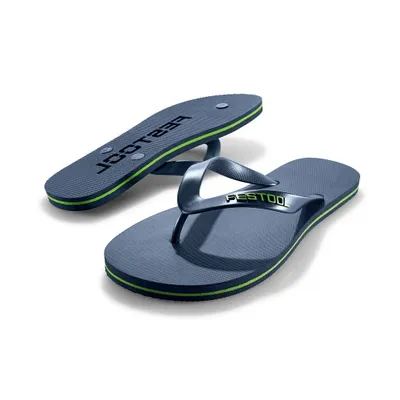 A pair of blue flip-flops with green trim, one is lying flat and the other is slightly elevated.
