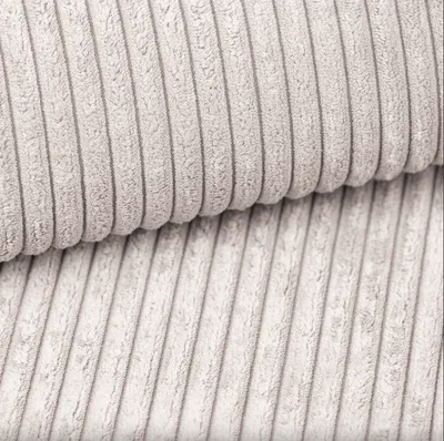 A close-up view of beige corduroy fabric, showing the texture and ribbed pattern.