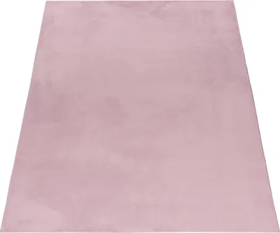 A pink rug is shown from a diagonal angle on a white background.