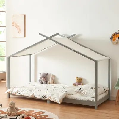 A child's bed with a house frame and canopy, decorated with stuffed animals and bedding, in a bedroom setting.