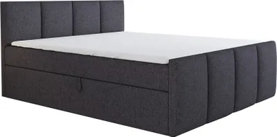 A dark gray upholstered boxspring bed with a white mattress and a tufted headboard, shown from a side angle against a white background.