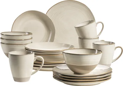 A collection of beige and brown stoneware dishes and mugs, arranged in a studio setting.