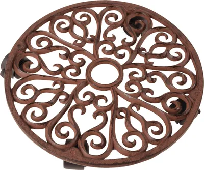 A round cast iron trivet with an ornate scrollwork design.