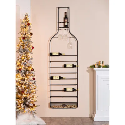 A wine rack shaped like a bottle is displayed on a wall next to a decorated Christmas tree and a fireplace.