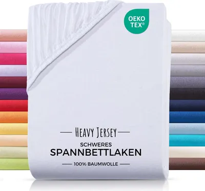 A white fitted sheet is folded and displayed prominently, with a stack of other colored fitted sheets visible on the left and right sides.