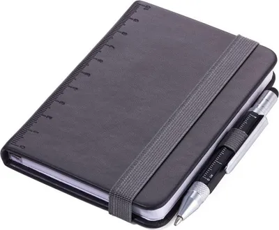 A black notebook with a ruler marking on the cover and a multi-tool pen attached by an elastic band.