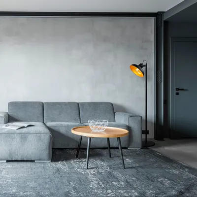 A modern living room with a gray sectional sofa, a wooden coffee table, and a floor lamp.