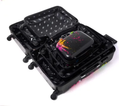 Several black suitcases of varying sizes are nested inside each other, with the largest one open. A smaller, black accessory case with colorful paint splatters is placed inside the largest suitcase.