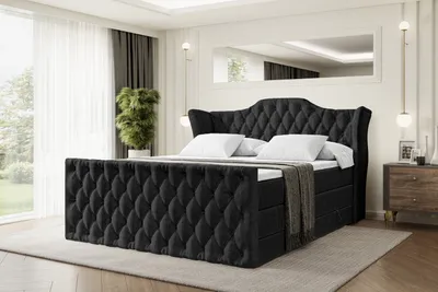 A black upholstered bed with a tufted headboard and footboard is displayed in a bedroom setting.