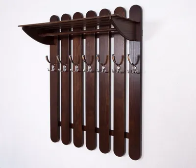 A wooden coat rack with a shelf is mounted on a white wall.