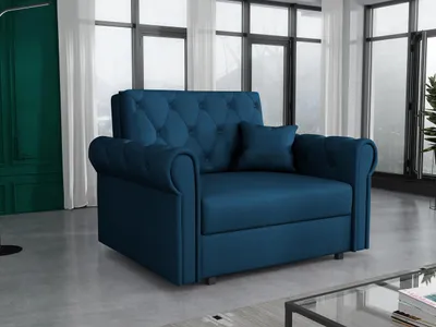 A blue sofa with tufted back cushions and rolled arms is shown in a living room setting with large windows in the background.