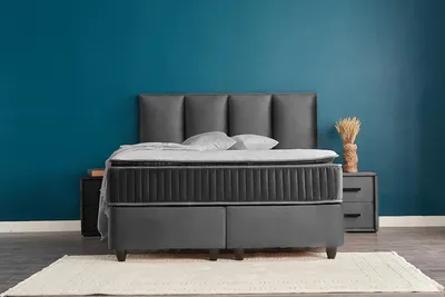 A bed with a headboard and two nightstands against a blue wall.