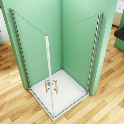 A corner shower cabin with glass doors and a white base, set against a light green wall and a wooden floor.