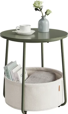 A round side table with a storage basket underneath, holding books and a blanket. A vase with flowers and a cup of coffee are on top.