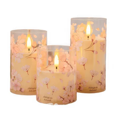 Three LED candles with a floral design are displayed against a white background.