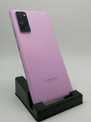 A purple Samsung Galaxy S20 FE 5G smartphone is displayed on a black stand against a white background.