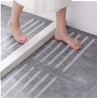 A person's feet are stepping on anti-slip stickers in a shower or bathtub area.