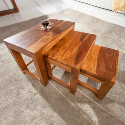 Three nested wooden tables of varying sizes on a carpet.