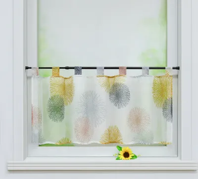 A short curtain with a colorful firework pattern hangs in a window.