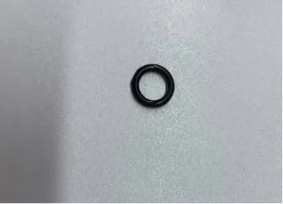 A single black O-ring is centered on a light gray textured surface.