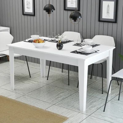 A white dining table set with place settings and a fruit bowl, in a dining room setting with grey paneled walls and pendant lights.