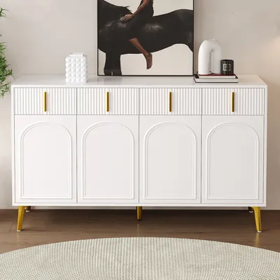 A white sideboard with gold handles and legs, placed in a room with a painting on the wall and a rug on the floor.