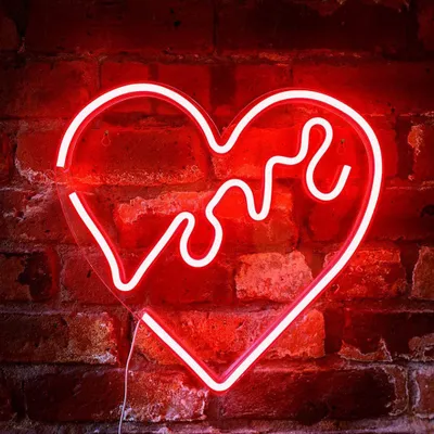 A red neon heart-shaped sign with the word 'Love' inside, mounted on a brick wall.