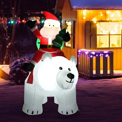 An inflatable Santa Claus riding a polar bear with a Christmas tree, set up as outdoor Christmas decoration in front of a house.