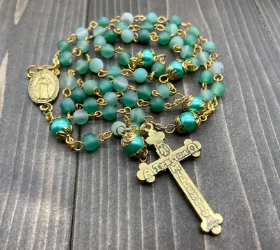 Imagen del producto de Cadena de Rosenkranz con cuentas de piedra mate, perlas verdes, una medalla y una cruz, todo ello en una bolsa de terciopelo