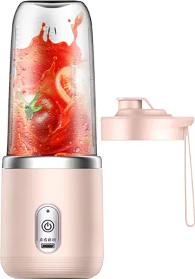A pink portable smoothie maker with a clear blending cup filled with tomatoes and juice, shown next to its pink lid.
