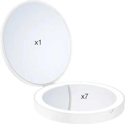 A white makeup mirror with two sides, one with normal magnification and the other with 7x magnification, is shown open against a white background.