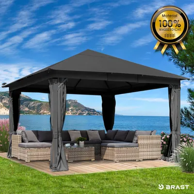 A gazebo with outdoor furniture set up on a wooden deck by the sea.