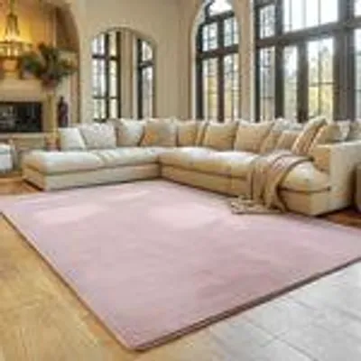 A spacious living room with a large sectional sofa and a pink rug.