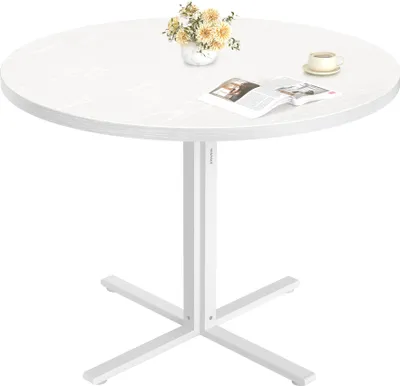 A round white table with a floral arrangement and a book on it.